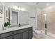 Well-lit bathroom featuring a gray vanity with a granite countertop and a glass-enclosed shower at 7500 Alpine Butterfly Ln, Orlando, FL 32819