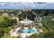 Aerial view of community pool with lush palms and landscaping, with clubhouse and condo building in the background at 812 Driving Range Ct, Reunion, FL 34747