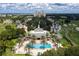 Aerial view of a clubhouse with a pool surrounded by palm trees, lush lawns, and manicured landscaping at 812 Driving Range Ct, Reunion, FL 34747