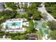 Aerial view of a community pool and mini golf course surrounded by manicured lawns, lush trees and town houses at 812 Driving Range Ct, Reunion, FL 34747