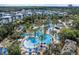Aerial view of the resort with swimming pools, palm trees, and blue sun umbrellas, surrounded by townhouses at 812 Driving Range Ct, Reunion, FL 34747