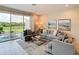Spacious living room featuring a comfortable gray sectional, a stylish rug, and sliding glass doors to the yard at 812 Driving Range Ct, Reunion, FL 34747