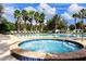 Relaxing pool area with jacuzzi and lounge chairs, surrounded by palm trees under a sunny blue sky at 812 Driving Range Ct, Reunion, FL 34747