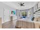 Bright main bedroom boasts wood floors, tray ceilings, a ceiling fan, dresser, and large windows at 8676 Currituck Sound Ln, Orlando, FL 32829
