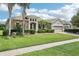 Inviting home exterior featuring stone accents, palm trees, manicured lawn, and a three-car garage at 9843 Nokay Dr, Orlando, FL 32836