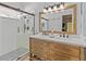 Bathroom featuring a double sink vanity with a wood frame mirror, a walk-in shower, and modern fixtures at 10124 Pink Carnation Ct, Orlando, FL 32825