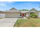 Charming single-story home with a well-maintained lawn, two-car garage, and a vibrant red front door at 10124 Pink Carnation Ct, Orlando, FL 32825