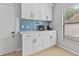 Coffee bar with white cabinets, blue backsplash, quartz countertops, and natural light from the window at 10124 Pink Carnation Ct, Orlando, FL 32825