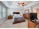 Carpeted bedroom with tray ceiling, ceiling fan, dresser, and TV at 1027 Cedar Bay Ln, Winter Springs, FL 32708