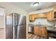 Well-lit kitchen with stainless steel refrigerator, granite countertops, and wood cabinets at 108 N Truett St, Leesburg, FL 34748