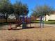 Colorful playground equipment on a wood chip ground surrounded by trees and grass at 1201 S Beach Cir, Kissimmee, FL 34746