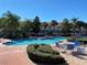 Community pool surrounded by palm trees, lounge chairs, and lush landscaping under a clear blue sky at 1201 S Beach Cir, Kissimmee, FL 34746