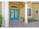 Close-up of an elegant entryway showcasing a blue double door framed by white columns and brick paving at 14545 Braddock Oak Dr, Orlando, FL 32837
