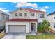 Charming two-story home featuring a red roof, two-car garage, and a beautifully landscaped front yard under a bright sky at 1744 Pine Ridge Dr, Davenport, FL 33896