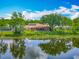 Lush backyard with a screened lanai overlooking a serene lake, reflecting the blue sky and trees at 1846 Branchwater Trl, Orlando, FL 32825