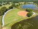 This aerial shows a well-maintained baseball field and the surrounding pond in the neighborhood at 25409 Waterbrook Ct, Leesburg, FL 34748