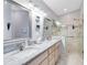Elegant bathroom featuring double sinks, granite counters, and a glass-enclosed shower at 25409 Waterbrook Ct, Leesburg, FL 34748
