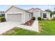 Charming home featuring a garage and well-manicured lawn, exuding curb appeal with beautiful walkway at 25409 Waterbrook Ct, Leesburg, FL 34748
