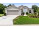 Charming home featuring a garage and well-manicured lawn, exuding curb appeal with beautiful walkway and lamp post at 25409 Waterbrook Ct, Leesburg, FL 34748