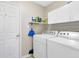 Functional laundry room with white washer, dryer, shelving, and storage at 25409 Waterbrook Ct, Leesburg, FL 34748