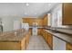 Kitchen featuring honey toned cabinets, an island with seating, tile backsplash, and stainless appliances at 2724 Amanda Kay Way, Kissimmee, FL 34744