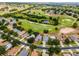 An aerial view shows a home with a well-kept lawn and a street lined with mature trees in a golf community at 3008 Pinnacle Ct, Clermont, FL 34711