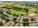 Aerial view shows a home with a well-kept lawn and a street lined with mature trees in a golf community at 3008 Pinnacle Ct, Clermont, FL 34711