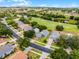 An aerial view showcases homes in a tranquil community near a lush golf course and pond at 3008 Pinnacle Ct, Clermont, FL 34711