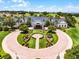 A community clubhouse shows professional landscaping with palms and manicured hedges in bricked roundabout at 3008 Pinnacle Ct, Clermont, FL 34711