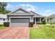 Charming single-story home featuring a brick driveway, attached garage, and beautifully landscaped front yard at 3008 Pinnacle Ct, Clermont, FL 34711