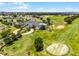 Expansive aerial view of a golf course community with a clubhouse, showcasing lush fairways and manicured landscaping at 3008 Pinnacle Ct, Clermont, FL 34711