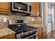 Close-up of a kitchen with a stainless steel oven, mosaic tile backsplash, granite countertops, and wooden cabinets at 3008 Pinnacle Ct, Clermont, FL 34711