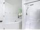 A full white bathroom featuring a walk in shower with an adjustable shower head and a soaking tub by a window at 310 Cornwallis Ct, Kissimmee, FL 34758