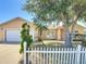 Charming single-story home with a well-manicured lawn, white picket fence, and attached two-car garage at 310 Cornwallis Ct, Kissimmee, FL 34758