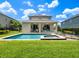 Beautiful backyard featuring a pristine pool and spa, lush grass, and a covered patio area at 311 W Falls Dr, Kissimmee, FL 34747