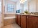 Bathroom featuring a double sink vanity with granite countertop, a soaking tub, and decorative wall art at 311 W Falls Dr, Kissimmee, FL 34747