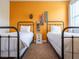 Bedroom with two twin beds, bright orange wall with skateboard decor, and carpeted floor at 311 W Falls Dr, Kissimmee, FL 34747