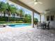 Outdoor patio with ceiling fans, dining table, and views of a beautiful private pool and tropical landscaping at 311 W Falls Dr, Kissimmee, FL 34747