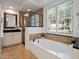 Bright bathroom featuring a soaking tub, glass shower, double vanity, and plantation shutters for a spa-like retreat at 3352 Park Grove Ct, Longwood, FL 32779