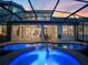 Inviting pool area with blue-lit pool, screened enclosure and seamless transition to indoor living and dining spaces at 3352 Park Grove Ct, Longwood, FL 32779