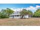 Charming exterior view of a white home, enhanced by a sprawling yard and mature trees at 511 E Mirror Lake Dr, Fruitland Park, FL 34731