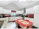 Bright kitchen features white cabinets, modern appliances, black countertops, and a red retro dining table at 511 E Mirror Lake Dr, Fruitland Park, FL 34731