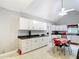 Bright kitchen featuring white cabinets, modern appliances, dark countertops, and a red retro dining table at 511 E Mirror Lake Dr, Fruitland Park, FL 34731