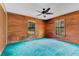Bedroom with wood walls, ceiling fan, plush turquoise carpet, and windows for natural light at 5180 Garlanger Trl, Oviedo, FL 32765