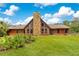 Charming log home featuring a stone chimney and lush green lawn under a bright blue, partly cloudy sky at 5180 Garlanger Trl, Oviedo, FL 32765