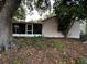 Home's back exterior featuring a screened lanai amidst overgrown plants, mulch, and trees at 567 Queensbridge Dr, Lake Mary, FL 32746