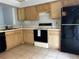 Well-lit kitchen area with oak cabinets, black appliances, and easy-to-clean tiled flooring at 567 Queensbridge Dr, Lake Mary, FL 32746