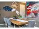 Chic dining room with a wooden table, gray chairs, modern lighting, and a vibrant abstract painting at 6543 Orange Cream Aly, Winter Garden, FL 34787