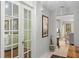 Hallway features neutral tones, artwork, a view of the living room through glass paneled doors, and tile flooring at 711 Valencia Ct, Winter Garden, FL 34787