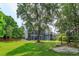 A beautiful home featuring a screened-in porch and a mature tree with Spanish moss in a lush backyard setting at 830 Miami Springs Dr, Longwood, FL 32779
